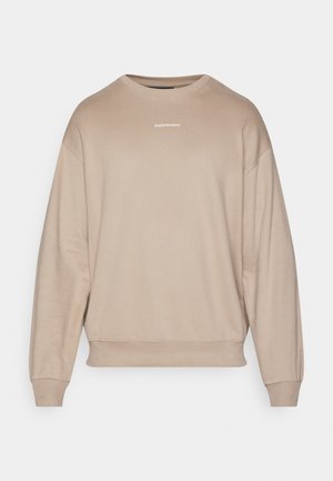 Béžová mikina s okrúhlym výstrihom a spustenými ramenami, s rebrovanými manžetami a lemom. Obsahuje malé biele logo umiestnené na hrudi. Mäkká textúra látky.