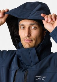 Navy blue jacket with a high collar and adjustable hood, featuring a zip closure. Material appears smooth with a matte finish.