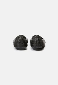 Chaussons en cuir matelassé noir avec une semelle plate, présentant un motif en losange et un design à bout arrondi, mettant en valeur une texture lisse et des accents subtils.
