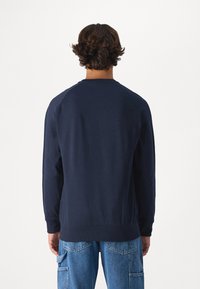 Sudadera de cuello redondo en color navy con mangas raglán y puños y dobladillo de canalé. Tela suave con una textura lisa, diseñada para la comodidad.
