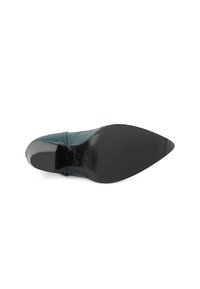 Zapato de punta afilada en cuero verde azulado con un acabado suave; presenta una suela exterior de goma negra con agarre texturizado y un leve tacón.