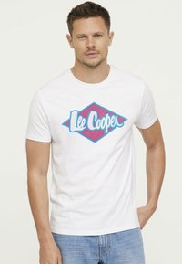 T-shirt blanc à manches courtes avec un logo en forme de diamant coloré et le texte "Lee Cooper" en bleu et rose. Fabriqué en coton avec une texture lisse.