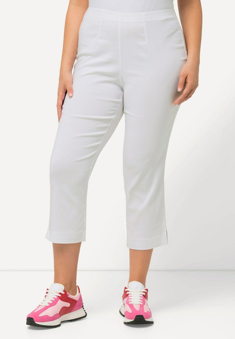 Witte cropped broeken met een zachte textuur, voorzien van een middelhoge tailleband en zijsplitten aan de zoom. Gepaard met kleurrijke sneakers.