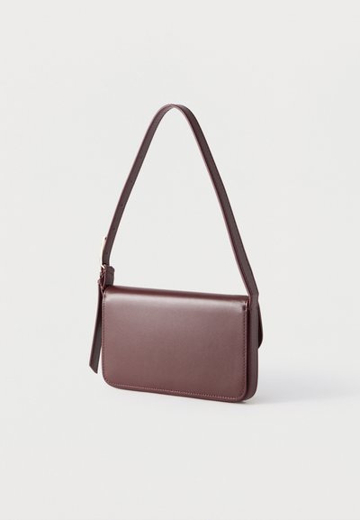 Σκούρα καφέ δερμάτινη τσάντα ώμου με ορθογώνιο σχήμα και έναν ρυθμιζόμενο ιμάντα, κρεμασμένη σε ανοιχτό φόντο.