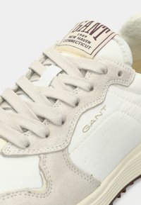 Ανοιχτό μπεζ και λευκό αθλητικό παπούτσι GANT με κορδόνια, λεπτομέρειες από σουέντ και ετικέτα που αναγράφει "GANT 1949 New Haven Connecticut."