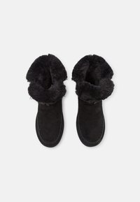 Botas negras hasta el tobillo con un cuello suave y esponjoso y material de ante. Cuentan con costuras a lo largo del borde y un interior texturizado.