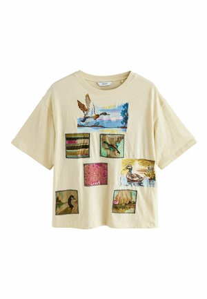 T-Shirt aus leichtem beigefarbenem Baumwollstoff mit mehreren Patches, die bestickte Enten, Texturen und Farben wie Grün, Pink und Braun zeigen.