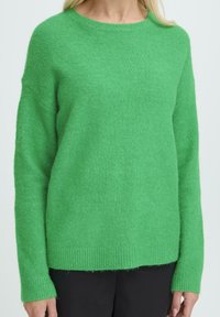 Pulover verde tricotat, realizat dintr-un material moale, texturat. Are un decolteu rotund și manșete și tiv cu nervuri, cu un croi lejer.