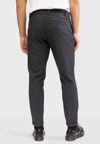 Pantalons taillés gris avec un tissu texturé, coupe slim et ourlets retroussés. Comprend deux poches arrière et un motif à carreaux subtil.