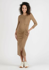 Umstandsabendkleid in Hellbraun, figurbetont mit rundem Halsausschnitt und Dreiviertelärmeln. Verfügt über Raffung und einen seitlichen Schlitz.