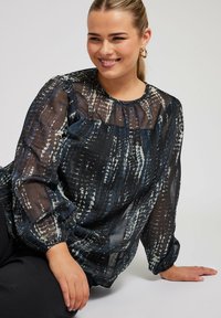 Durchsichtige schwarze Bluse mit einem filigranen blau-weißen Muster, puffigen langen Ärmeln und einem gerafften Ausschnitt. Glatter, leichter Stoff.