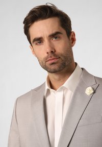 Light gray suit jacket with a tailored fit, white dress shirt, and a white floral lapel pin. Smooth fabric with subtle texture.