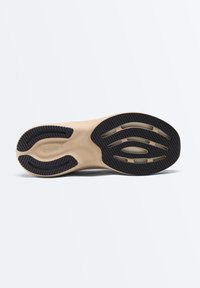 Semelle de chaussure beige et noire avec des motifs de grip texturés et le nom de la marque "OYSHO" embossé près de la zone du talon.
