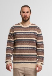Maglione a righe in beige, marrone e blu navy. Presenta un classico collo a giro e polsini e orlo a coste. Tessuto lavorato a maglia con motivi diagonali.