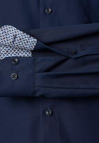 Navyblaues Hemd mit Knöpfen und einem gemusterten hellblauen und weißen Aufschlag. Verfügt über schwarze Knöpfe und eine glatte, weiche Stofftextur.