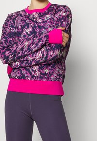 Bedruckter Sweatshirt mit einem dynamischen lila-rosa Muster, einem einfarbigen rosa Kragen und Bündchen, gefertigt aus weichem Stoff mit geripptem Saum.
