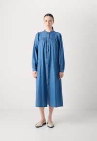 Jean haljina, duge rukave, gumba naprijed, dva bočna džepa, blago labav kroj, svijetloplava boja, teksturirana tkanina.