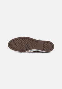 Semelle de sneaker en caoutchouc marron avec un motif texturé et un bord blanc. Présente un design de semelle en diamant et en lignes horizontales pour une meilleure adhérence.