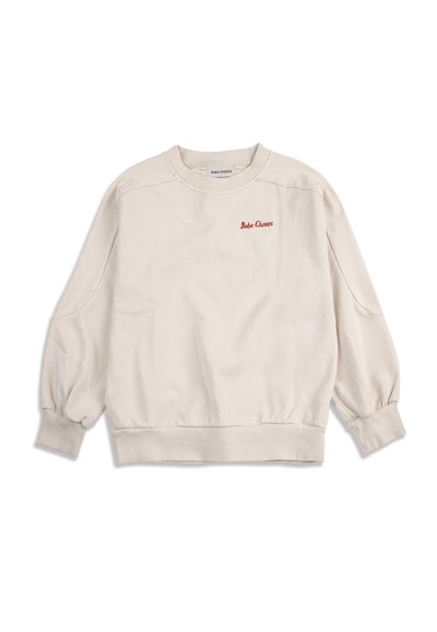 Sweat-shirt beige à manches longues avec col rond, poignets et ourlet côtelés, comportant un petit texte rouge "Bobo Choses" sur le côté gauche de la poitrine.