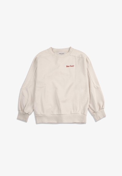 Sweat-shirt beige à manches longues avec col rond, poignets et ourlet côtelés, comportant un petit texte rouge "Bobo Choses" sur le côté gauche de la poitrine.