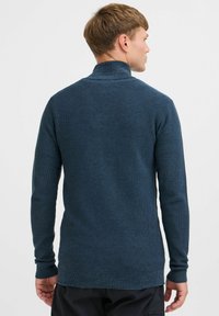 Sweter dzianinowy w ciemnoniebieskim kolorze z wysokim kołnierzem, długimi rękawami i fakturowanym wzorem. Dopasowany krój z prążkowanymi mankietami i dołem.