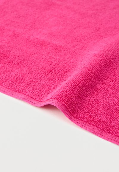 Φωτεινό ροζ πετσέτα από περκάλι με απαλή, υφή επιφάνεια, απλωμένη επίπεδη σε λευκό φόντο.