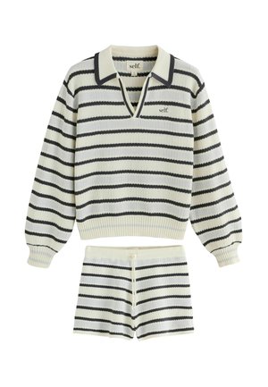 Langärmliger cremefarbener Strickpullover mit schwarzen horizontalen Streifen und passenden gestreiften Strickshorts mit Kordelbund.