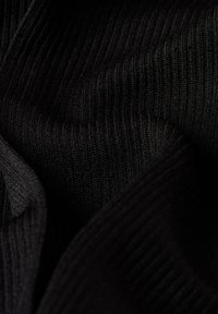 Zwarte ribbel stof met een gladde textuur, die fijne verticale lijnen en zachte draping toont. Geschikt voor kleding of accessoires.