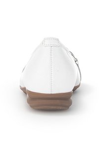 Weiße Lederflats mit runder Zehenpartie und brauner, niedriger Sohle, ausgestattet mit dezenten Nähten und einer glatten Textur im oberen Bereich.