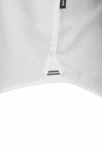 Witte shirt met een gestructureerde stof, met een split aan de onderkant en een marineblauw-wit gestreepte accenten aan de binnenkant. Het label is zichtbaar aan de zijnaad.