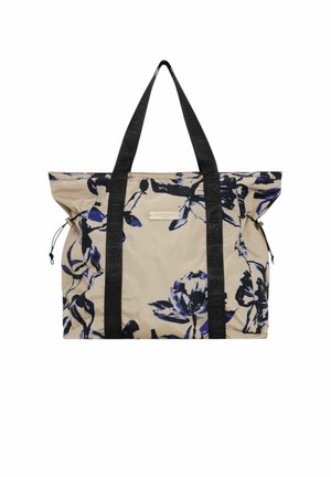 Beige fabric tote bag with black floral print, black straps with embossed brand name, and side drawstring closures. Features a zippered pocket.