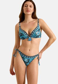 Blauwe bloemenbikini met een driehoekstop met een kwastdetail en lage taille onderkant, beide versierd met ingewikkelde patronen en strikken.