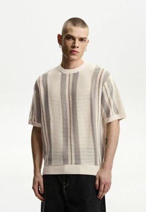 Textured, knitted sweater in light beige, featuring horizontal and vertical stripes in darker tones. Ribbed crew neck and short sleeves.