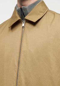 Ταμπά μπουφάν με φερμουάρ και υφασμένο σχέδιο, με γιακά και γκρι εσωτερική επένδυση. Το μπουφάν διαθέτει ασημένιο φερμουάρ και κομψό σχεδιασμό.