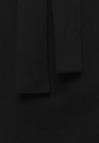 Tissu noir avec une texture lisse, comportant des sections drapées et une coupe droite, mettant en valeur une surface uniforme et l'absence de motifs.