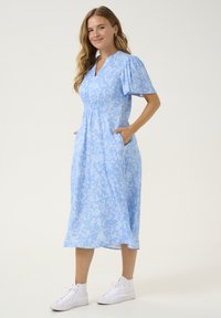 Abito midi azzurro chiaro con motivo floreale, dotato di maniche a sbuffo corte, scollatura a V e tasche laterali. Realizzato in un tessuto morbido e fluente.