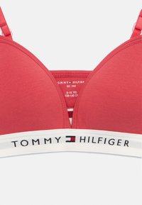 Ροζ επενδεδυμένο σουτιέν με ρυθμιζόμενους ιμάντες και λευκή ελαστική ταινία που φέρει το λογότυπο και το έμβλημα σημαίας της Tommy Hilfiger.