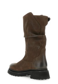 Bota de cuero marrón con un diseño despejado, suela negra gruesa, parte superior texturizada y una tira en la parte trasera. Presenta una punta redonda.