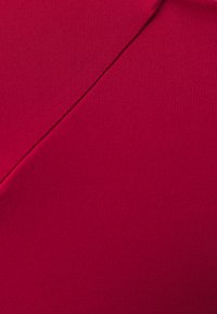 Red stretch fabric with a smooth texture, featuring an angled seam detail. The material appears lightweight and evenly colored.