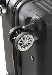 Valigia nera con superficie testurizzata, dotata di una ruota grigia con un design a raggi in argento e un mozzo in plastica nera. Dettagli con zip e bottone visibili.