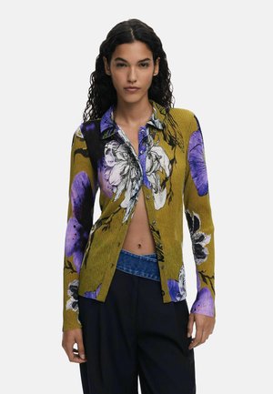 Cardigan giallo a coste con motivo floreale viola e nero, maniche lunghe, chiusura con bottoni sul davanti e dettaglio contrastante sul colletto.