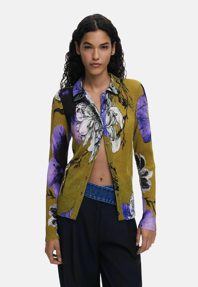 Cardigan giallo a coste con motivo floreale viola e nero, maniche lunghe, chiusura con bottoni sul davanti e dettaglio contrastante sul colletto.