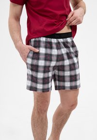 Szorty w kratkę w czarno-biało-czerwonym wzorze, z elastycznym pasem i bocznymi kieszeniami. Wykonane z bawełny dla wygody i wentylacji.