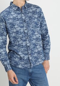 Blaues Langarm-Hemd mit Knöpfen und tropischem Blattmuster, aus leichtem Stoff gefertigt. Verfügt über eine Brusttasche und einen klassischen Kragen.