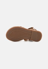 Brun sandalsåle, teksturert gummimateriale med riller. Rund form med flat hæl, designet for komfort og grep.