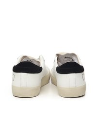 Witte leren sneakers met een zwart suède hielaccent, rubberen zool en een minimalistisch ontwerp met logo-detail op de achterkant.