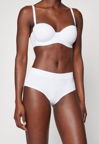 White padded bra with adjustable straps and high-waisted brief. Smooth fabric, seamless design, and minimalistic style.
