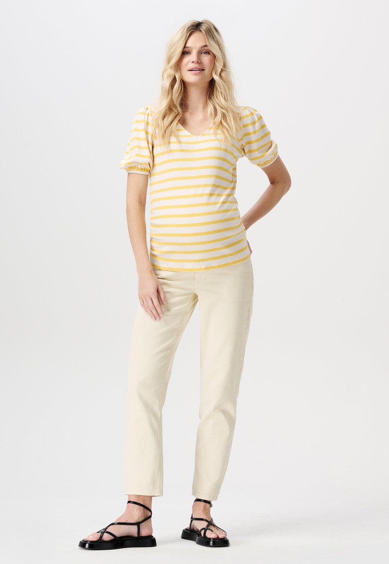 Gul och vitrandig kortärmad topp med V-halsringning, ihopparad med ljusbeiga raka byxor och svarta sandaletter med remmar.