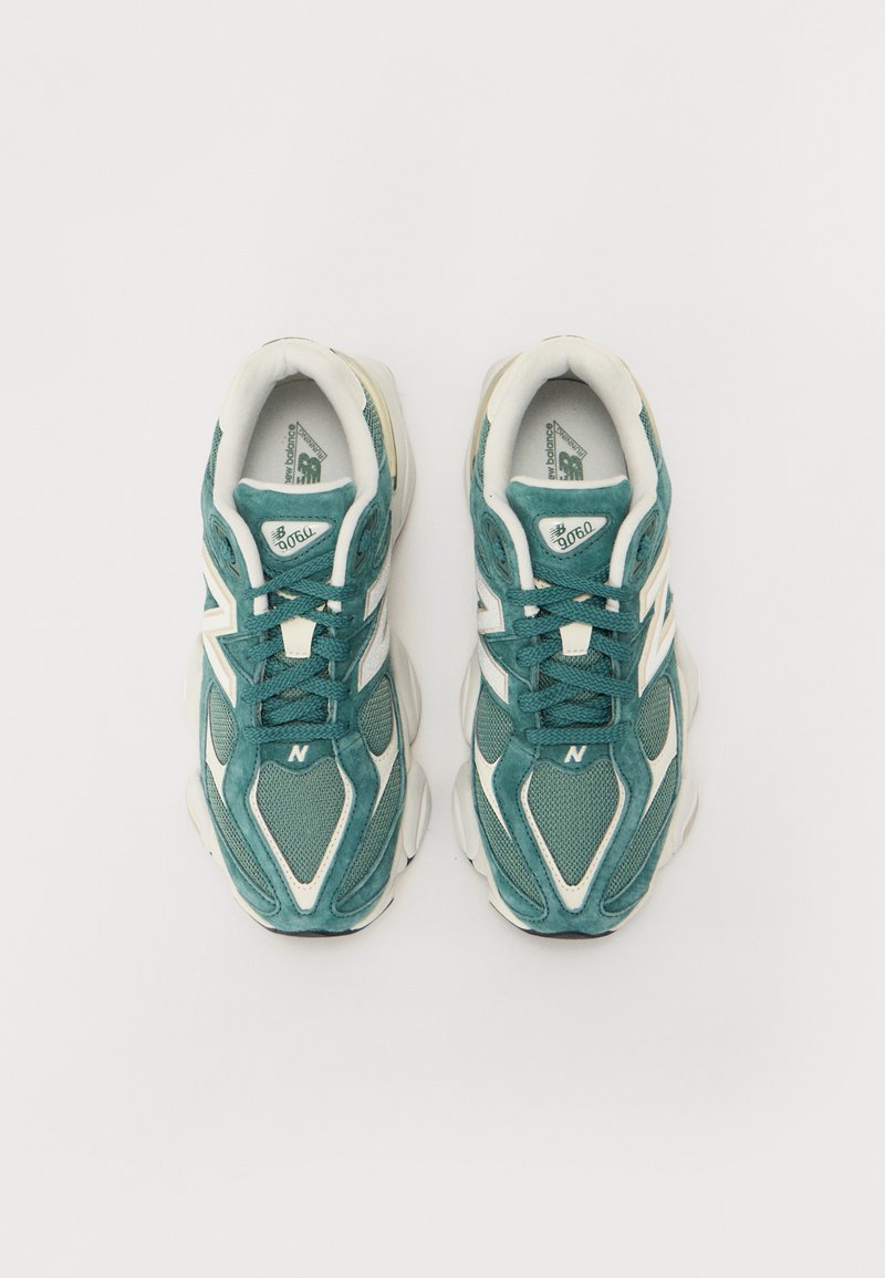 Türkise und weiße Sportschuhe aus Mesh und Wildleder, mit einer strukturierten Sohle und dem Buchstaben "N"-Logo an der Seite.