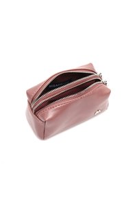 Malý obdélníkový taštička z fialového kožešiny s dvoma striebornými zipsami, které sú čiastočne otvorené, a zobrazuje čiernu etiketu vo vnútri.